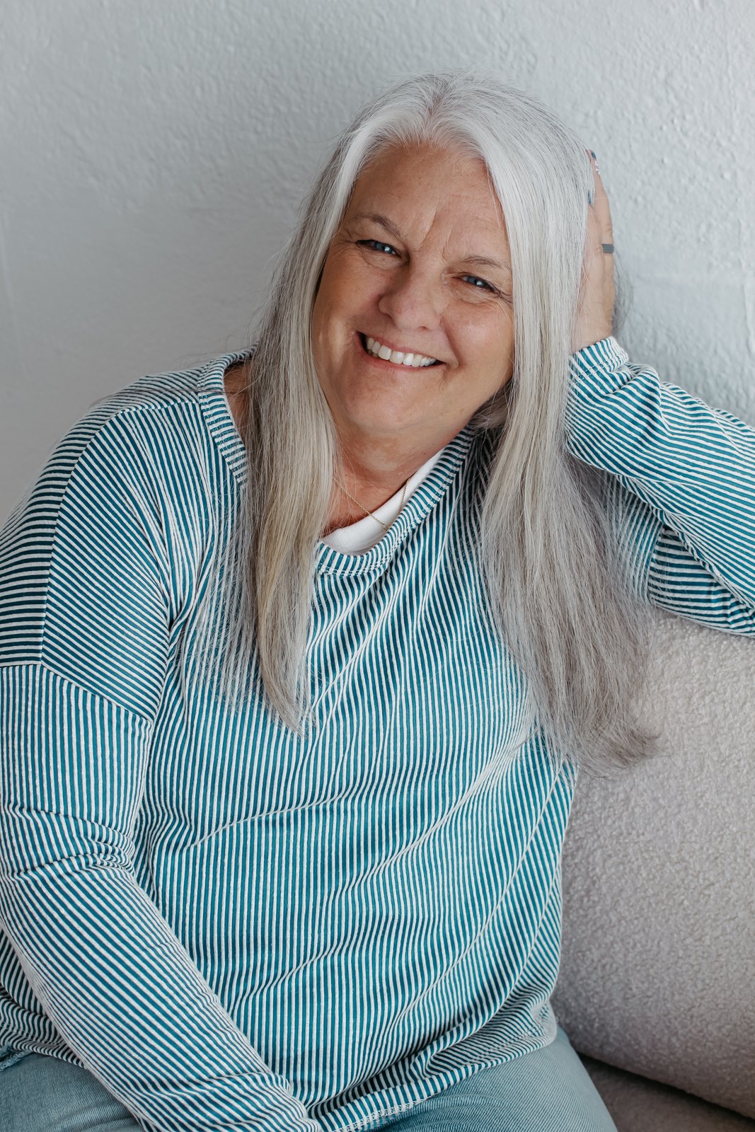 Linda, smiling warmly, relaxed on the sofa