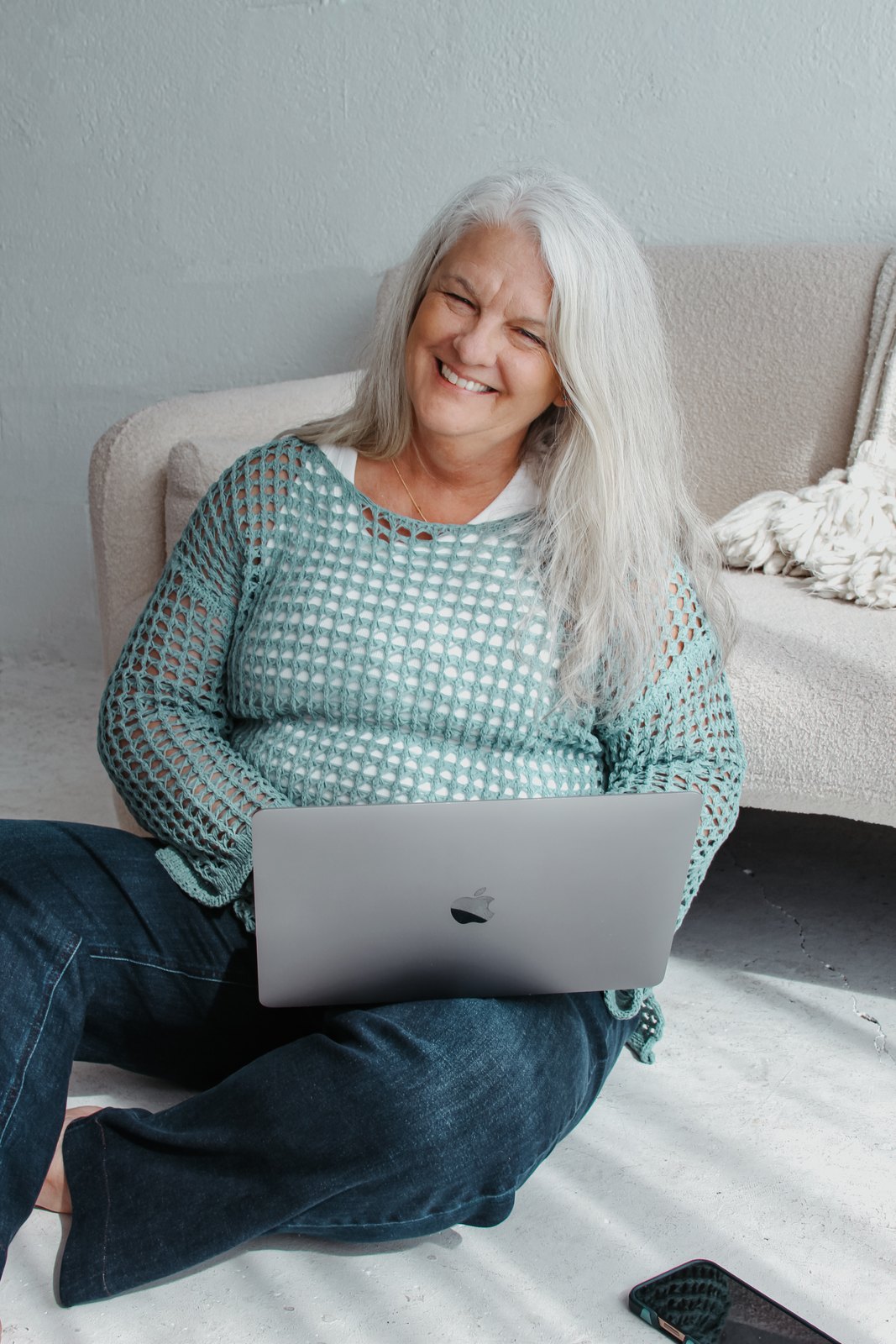Linda, laughing warmly, working on her laptop